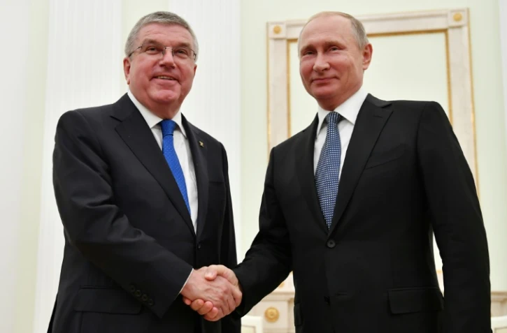 Le président russe Vladimir Poutine (d.) serre la main du président du Comité international olympique (CIO) Thomas Bach lors de leur rencontre au Kremlin à Moscou, le 15 juillet 2018