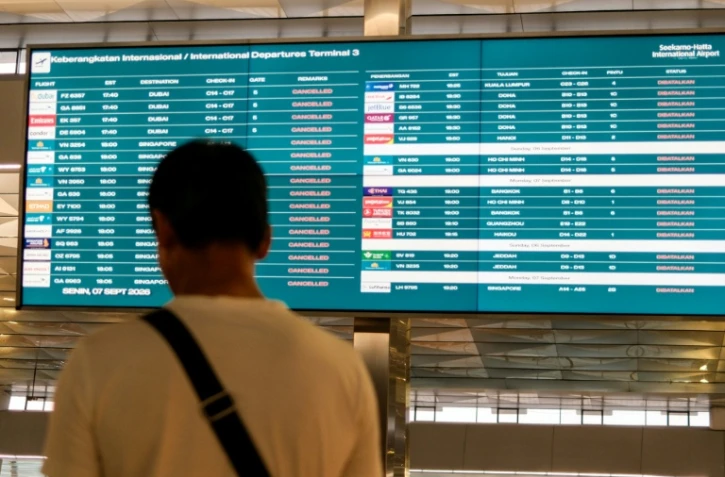 Un passager bloqué à l'aéroport international Soekarno-Hatta en raison de l'éruption du volcan Anak Krakatau, regarde un écran d'information sur les vols, le 7 septembre 2026 à Tangerang, en Indonésie