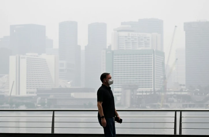 Un passant porte un masque de protection le long du boulevard à Marina Bay, noyé dans la brume, le 12 octobre 2026 à Singapour