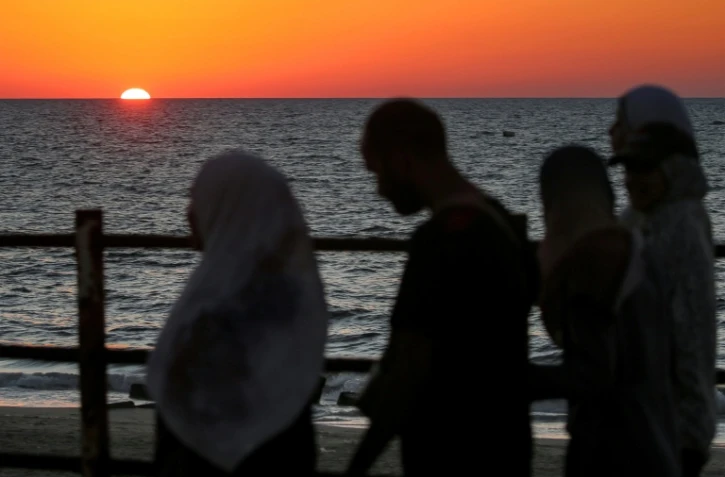 Le soleil se couche sur la mer Méditerranée alors que des Palestiniens déplacés évacuent la ville de Gaza vers le sud de la bande de Gaza face aux bombardements israéliens, le 13 septembre 2025 dans la bande de Gaza