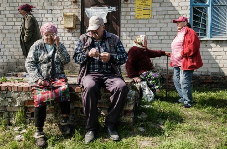 Des personnes âgées attendent de recevoir leur pension à côté d'un camion postal qui est parvenu à se rapprocher de la ligne de front à Mayaky, est de l'Ukraine, le 6 mai 2022