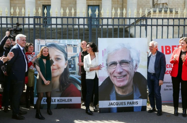 Cécile Kohler (3e G) et Jacques Paris (2e D) devant leurs portraits décrochés des grilles de l'Assemblée nationale, à Paris le 14 avril 2026