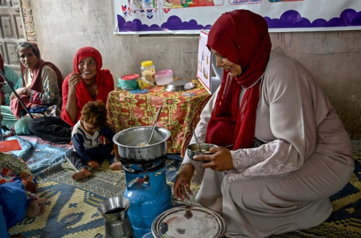 Une travailleuse sociale (d) montre à des mères comment préparer des repas nutritifs pour leurs enfants lors d'un programme de nutrition de l'Unicef au village de Fateh Muhammad Soomro, dans la province du Sindh, le 29 juillet 2025 au Pakistan