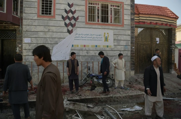 Des Afghans sur les lieux d'un attentat suicide contre un centre d'enregistrement électoral, le 22 avril 2018 à Kaboul