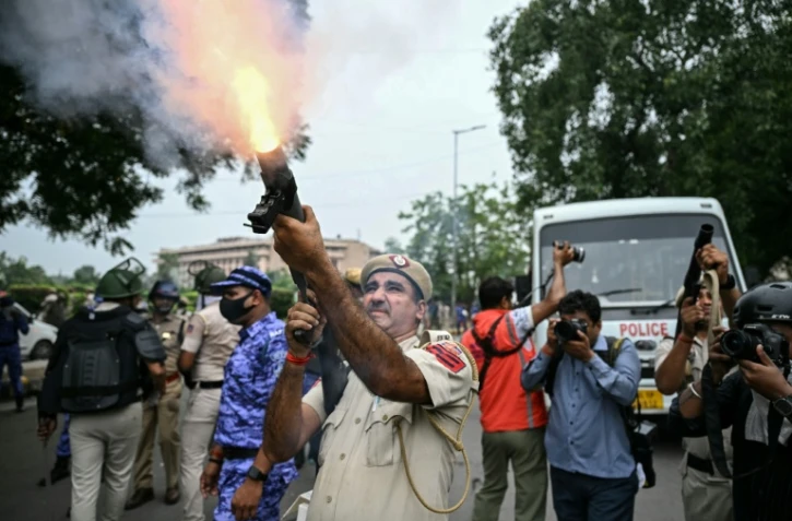 Un policier tire des grenades lacrymogènes pour disperser des militants du "Parti du peuple des cafards" (CJP) lors d'une manifestation réclamant la démission du ministre de l'Éducation, Dharmendra Pradhan, en raison de fraudes présumées aux examens universitaires, le 20 juillet 2026 à New Delhi, en Inde