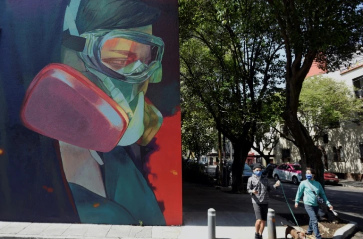 Passants près d'une fresque à Mexico, le 9 juin 2020