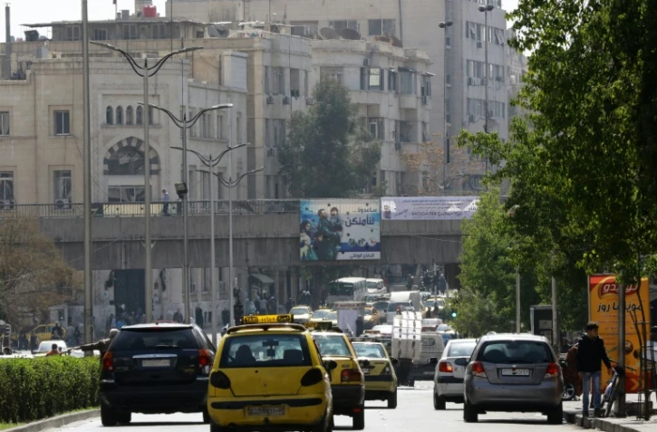 Des véhicules circulent dans une rue de Damas le 27 février 2016