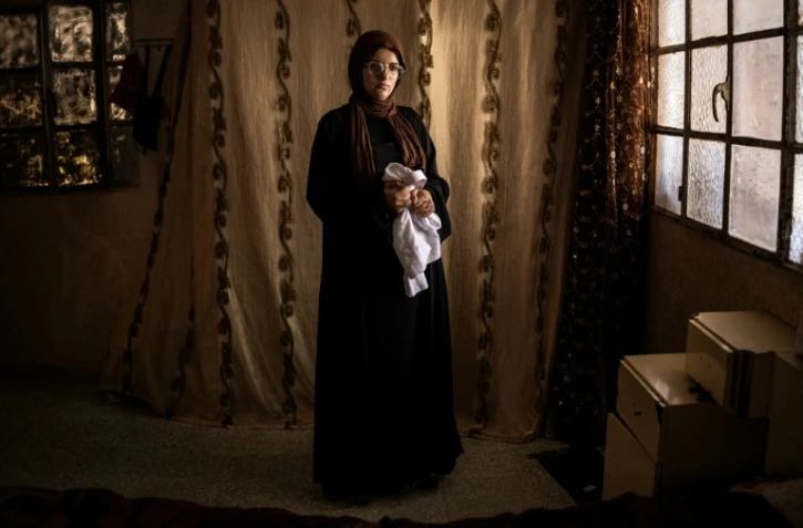 Alia al-Hallaq, la mère de Mohammed, tué à 9 ans par un soldat israélien en octobre 2025, tient le thobe de son fils, dans le village d'al-Rihiya, en Cisjordanie occupée, le 16 juillet 2026