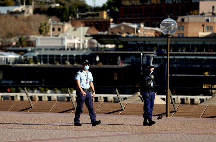 Des policiers patrouillent dans le quartier de l'opéra de Sydney, où le confinement a été prolongé pour au moins deux semaines