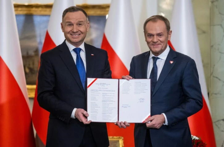 Le président polonais Andrzej Duda (g) et le nouveau Premier ministre, Donald Tusk, lors de la prestation de serment du gouvernement au palais présidentiel, le 13 décembre 2023 à Varsovie