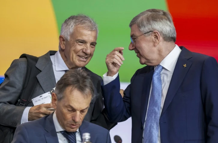 Le candidat espagnol à la présidence du Comité international olympique (CIO) Juan Antonio Samaranch Jr (g.) s'entretient avec le président sortant, l'Allemand Thomas Bach (d.), à côté du directeur général, le Belge Christophe De Kepper (c.), lors de la 144e session du CIO à Costa Navarino (Grèce), le 19 mars 2025