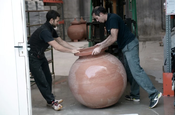  Inaki Goicoechea (g) et un artisan potier manipulent une jarre en terre cuite dans lequel ils font du vin à la manière des viticulteurs géorgiens, dans son atelier à Ossès ( sud-ouest de la France), le 12 octobre 2017