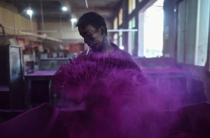 Un travailleur couvre des bâtonnets d'encens avec de la poudre colorée dans une fabrique à Quanzhou, en Chine