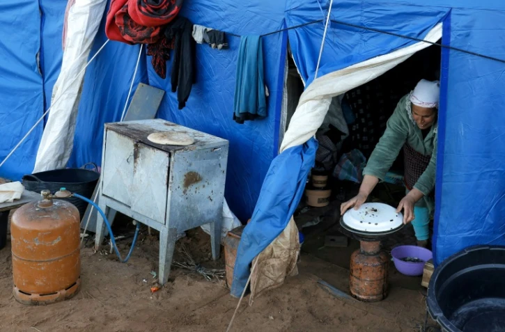 Une femme prépare à manger dans l'une des tentes d'un camp destiné aux personnes touchées par les inondations qui ont frappé le nord et l'ouest du Maroc, dans la région de Kénitra, le 20 février 2026