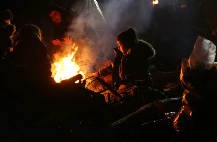 Des migrants se réchauffent près d'un feu le 14 novembre 2021 à la frontière entre le Bélarus et la Pologne