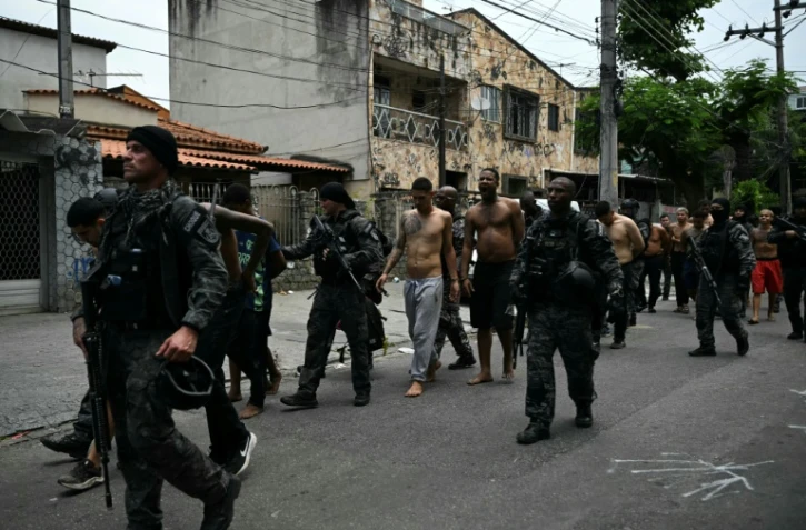 Des policiers escortent des criminels présumés arrêtés lors d'une opération dans la favela de Vila Cruzeiro, dans le complexe de Penha, à Rio de Janeiro, le 28 octobre 2025 au Brésil