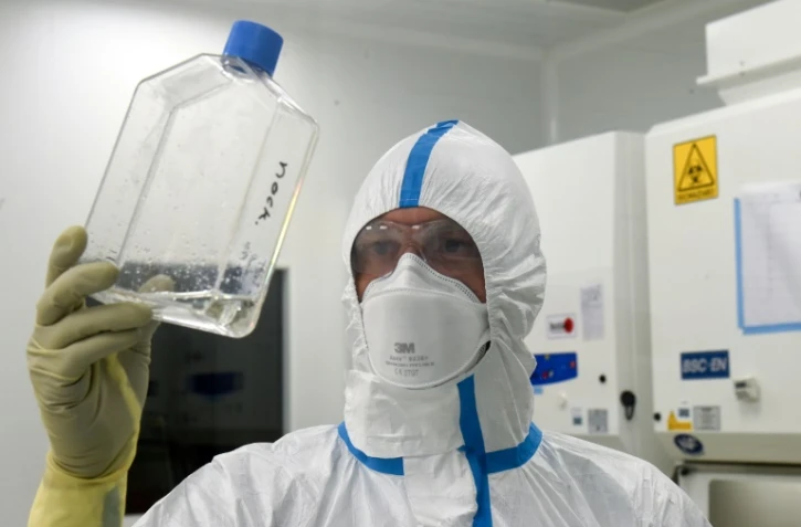 Un techncien examine un flacon contenant un liquide infecté par le virus du Sars-Cov-2 dans le laboratoire de la société de biotechnologie Valneva, le 30 juillet 2020 à Saint-Herblain, près de Nantes