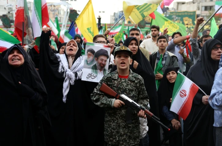 Un jeune Iranien en uniforme militaire brandit un fusil factice lors d'un rassemblement des partisans du pouvoir, le 29 avril 2029 à Téhéran