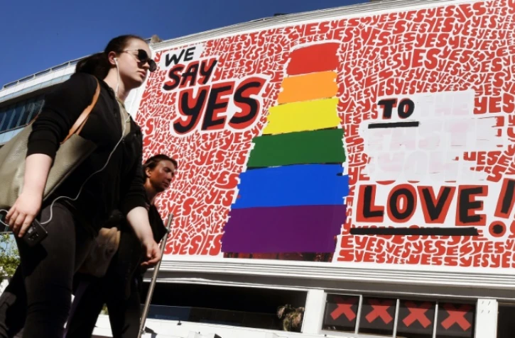 Des personnes passent devant un immense panneau d'affichage pour le "oui" au mariage gay à Sydney le 14 bovembre 2017