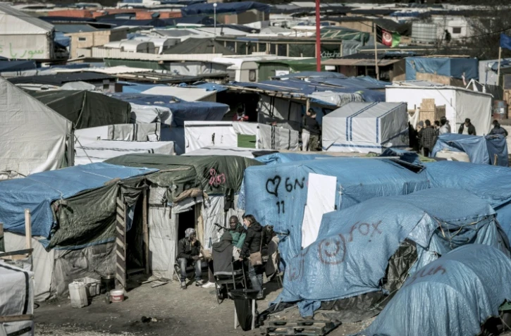 Des migrants discutent à l'extérieur de leurs tentes dans la Jungle de Calais, en France, le 30 mars 2016