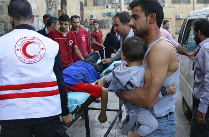 Un Syrien porte un enfant dans ses bras en attendant d'avoir accès à un hôpital le 13 octobre 2016 à Alep en Syrie