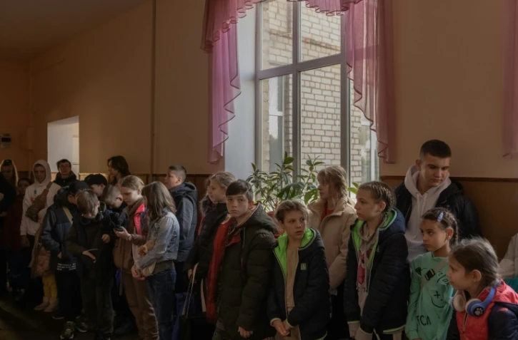 Des enfants attendent leur évacuation dans le couloir d'une école à Kherson, le 30 octobre 2023 en Ukraine