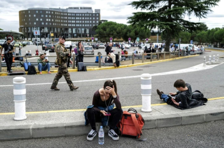 Des voyageurs attendent à l'extérieur de l'aéroport de Toulouse-Blagnac évacué après une alerte à la bombe, le 18 octobre 2023