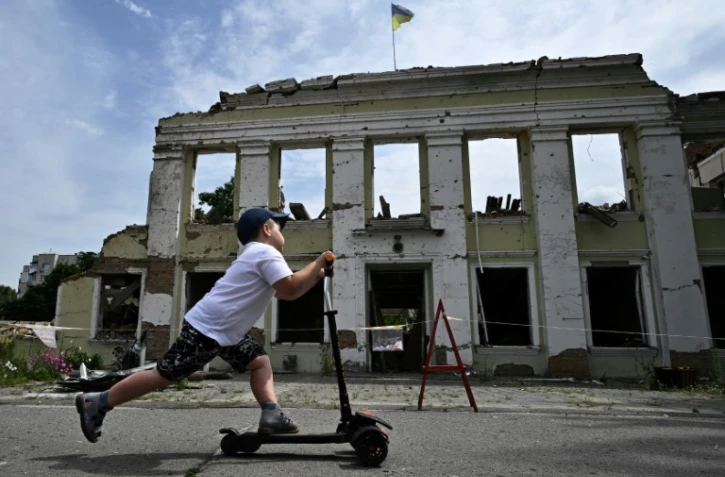 Un enfant passe trottinette devant les ruines de la mairie d'Okhtyrka, le 1er août 2022 en Ukraine 
