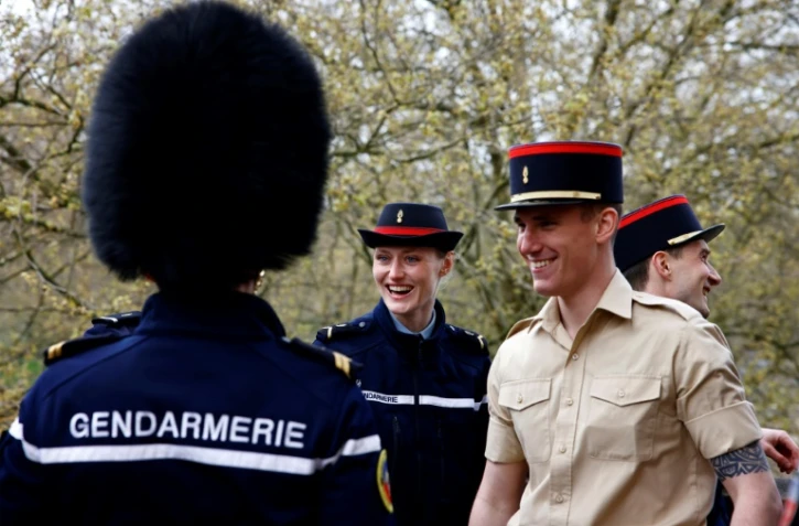 Un membre de la Garde Républicaine française échange son chapeau avec un membre de la "Number F Company Scots Guards" de l'armée britannique, à Wellington Barracks, à Londres, le 5 avril 2024