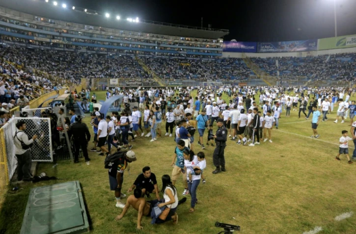 Des supporters sur la pelouse du stade Cuscatlan après une bousculade pendant un match de football entre Alianza et FAS , le 20 mai 2023 à San Salvador
