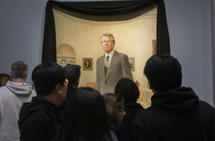 Les visiteurs du musée Smithsonian National Portrait Gallery contemplent un portrait de Norman Rockwell de l'ancien président américain Jimmy Carter dans le bureau ovale de la Maison Blanche, drapé d'un drap de deuil noir, à Washington, aux Etats-Unis, le 30 décembre 2024