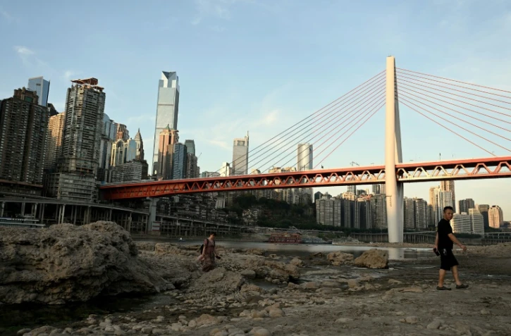 Des passants traversent le lit asséché de la rivière Jialing, un affluent du fleuve Yangtsé, dans la ville de Chongqing en Chine, le 24 août 2022