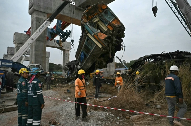 Des secouristes sur le site du déraillement d'un train provoqué par l'effondrement d'une grue de chantier dans la province de Nakhon Ratchasima, en Thaïlande, le 14 janvier 2026