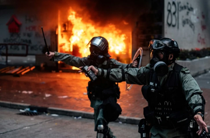 Policiers hongkongais devant un immeuble dont l'entrée est feu, après des heurts avec des manifestants, le 29 septembre 2019
