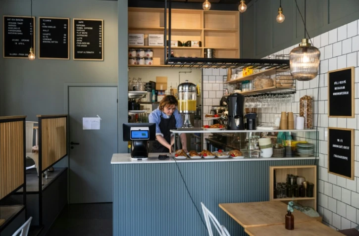 Kajetan Grzelczak derrière son comptoir  au café Andon à Stockholm, entièrement dirigé par l'IA, le 27 avril 2026