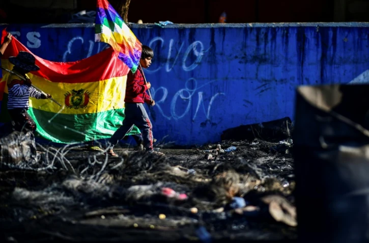 Un garçon tient le drapeau Wiphala, la bannière multicolore des peuples indigènes andins, sur un barrage routier installé par des partisans de l'ex-président bolivien Evo Morales à Sacaba, près de Cochabamba, le 18 novembre 2019