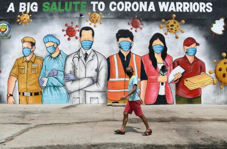 Un homme passe dant une fresque murale qui rend hommage aux "guerriers du corona", le 31 mai Ă New Delhi