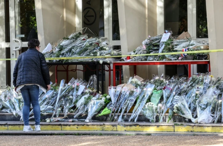 Une personne rend hommage devant le collège-lycée d'Arras, le 15 octobre 2023,  au professeur tué Dominique Bernard