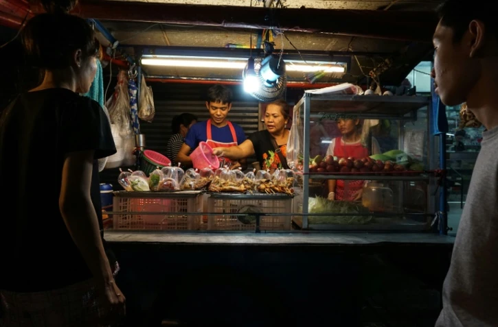 Une famille de vendeurs de rue prépare de la nourriture, le 17 avril 2017 à Bangkok