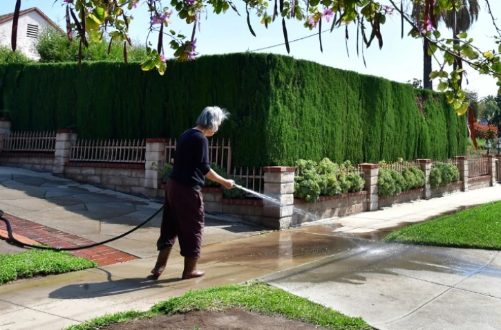 Une habitante arrose son allée à Monterey Park, en Californie, le 27 avril 2022