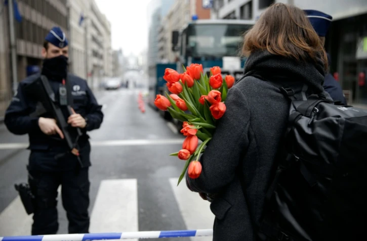 Une femme arrive avec des fleurs à la station de métro de Maelbeek le 23 mars 2016 à Bruxelles