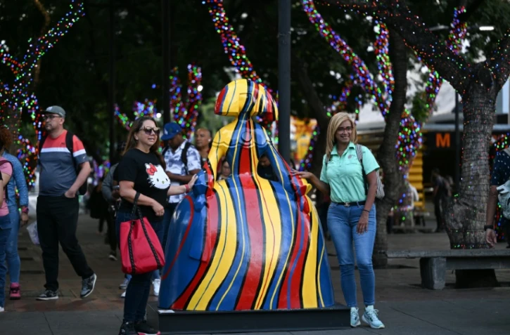 Des passantes à côté de l'une des sculptures réalisées par l'artiste vénézuélien Antonio Azzato dans le cadre de l'exposition de rue "Meninas Caracas Gallery", le 10 janvier 2024 à Caracas, au Venezuela