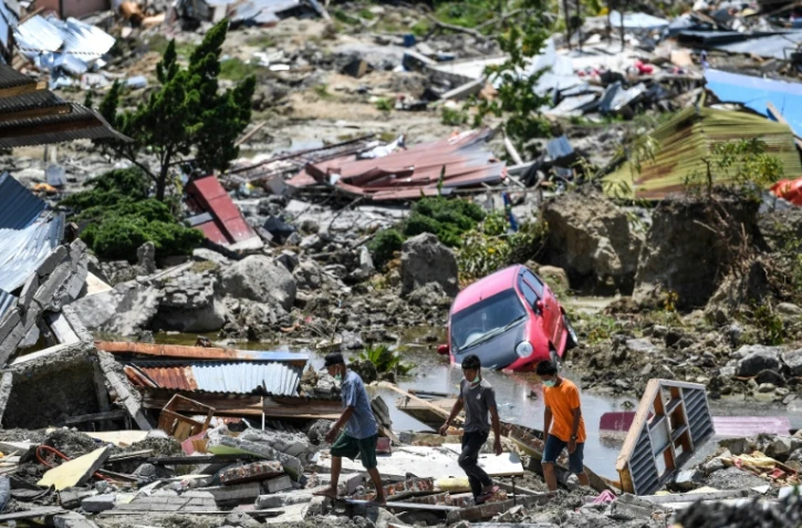 Des rescapés passent au milieu des décombres d'habitations à Palu le 2 octobre 2018, frappé par un séisme et un tsunami le 28 septembre.
