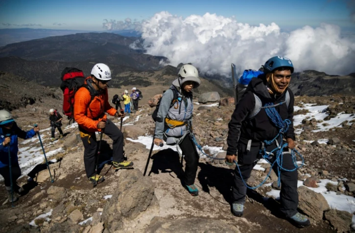 Ximena Gutierrez (c), amputée d'une jambe après un cancer des os, grimpe avec des béquilles accompagnée de ses guides vers le sommet du pic d'Orizaba (5.610 m), le plus haut du Mexique, le 24 novembre 2023