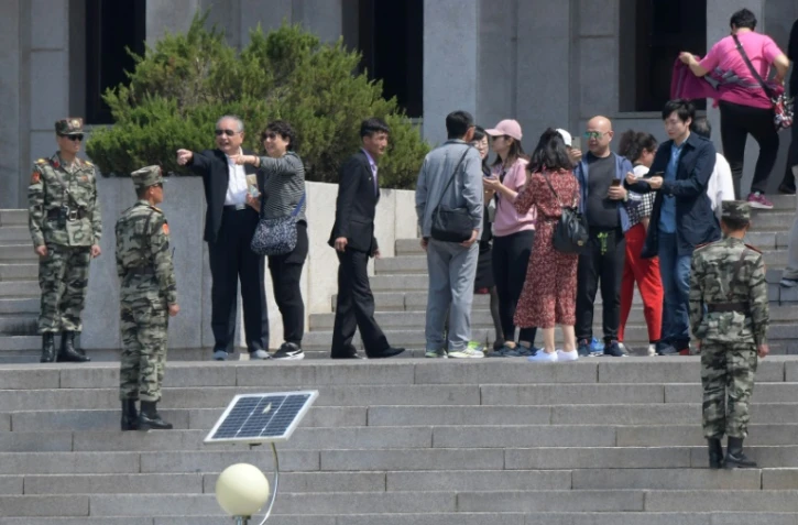 Des soldats nord-coréens montent la garde du côté nord du la frontière tandis que des touristes visitent le village de Panmounjom