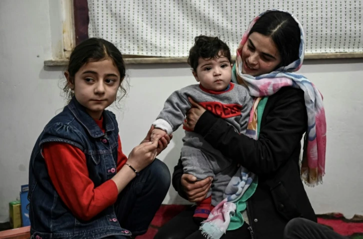 Sohail Ahmadi (C), séparé de sa famille dans le chaos des évacuations à l'aéroport de Kaboul en août 2021, retrouve les siens chez son grand-père à Kaboul le 9 janvier 2022