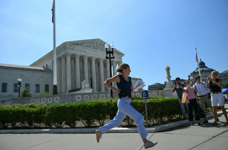 Une journaliste court devant la Cour suprême des États-Unis après qu'elle a rejeté la tentative du président Donald Trump de restreindre l'acquisition de la citoyenneté par le droit du sol, le 30 juin 2026 à Washington