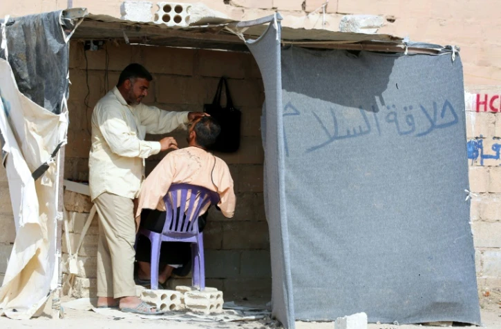 Un réfugié irakien qui a fui la ville Mossoul, sous contrôle de l'EI, rase la barbe d'un autre réfugié dans le camp Al-Hol, à Al-Hawl, en Syrie, le 25 octobre 2016
