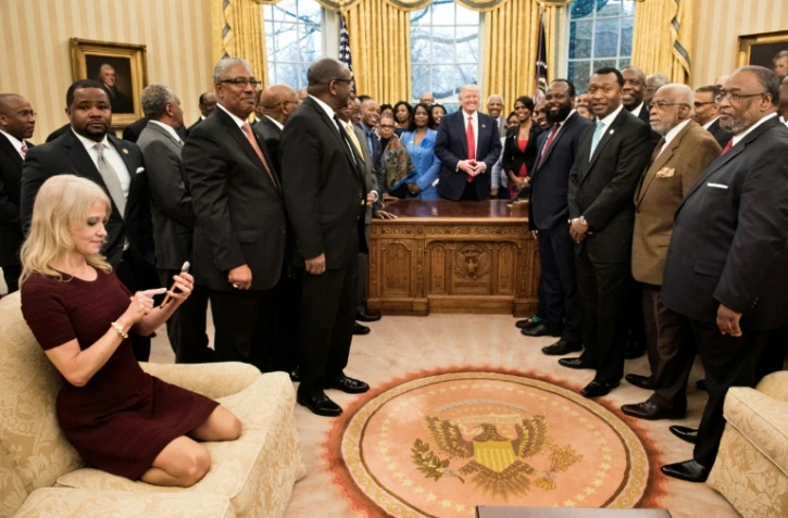 La conseillère du président américain Donald Trump, Kellyanne Conway (g), agenouillée sur un sofa pour prendre une photo du président, le 27 février 2017 dans le Bureau Ovale de la Maison Blanche