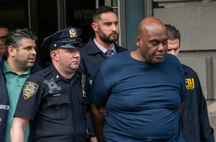 Frank James (c) soupçonné d'avoir tiré dans le métro de New York, escorté par des policiers peu après son arrestation, le 13 avril 2022